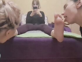 Two female slaves lick their mistress's soles at the same time